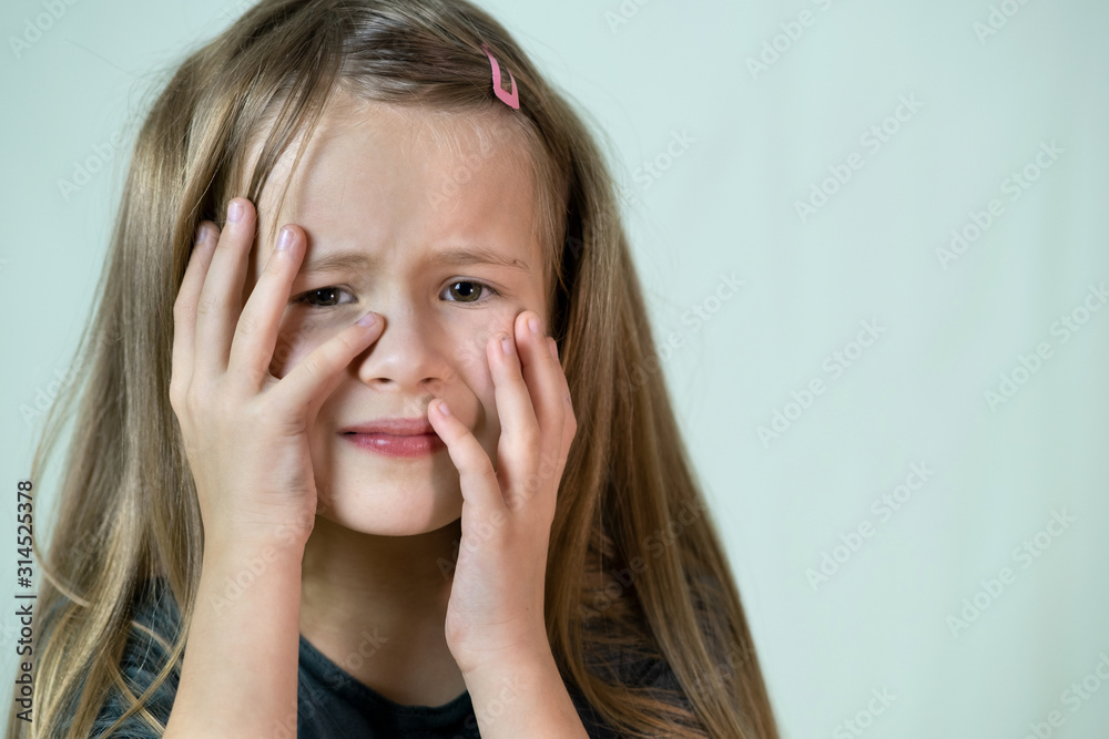 Close-up portrait of unhappy little girl with long hair covering her face with hands crying. Close-up portrait of unhappy little girl with long hair covering her face with hands crying.