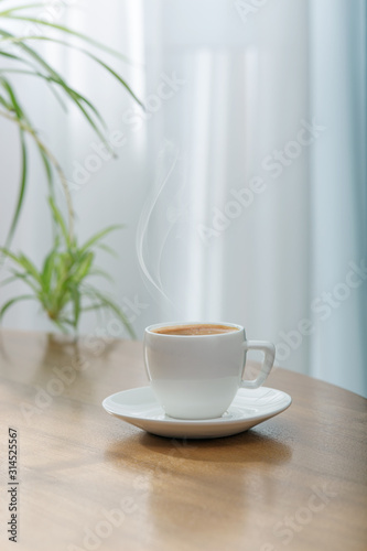 Fresh aromatic coffee in a white ceramic cup on a wooden table.