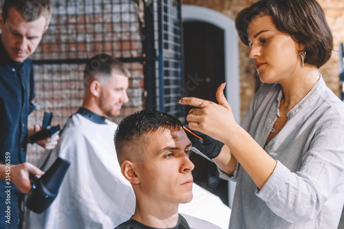 Hairdressers cut their clients in barbershop. Advertising and barber shop concept
