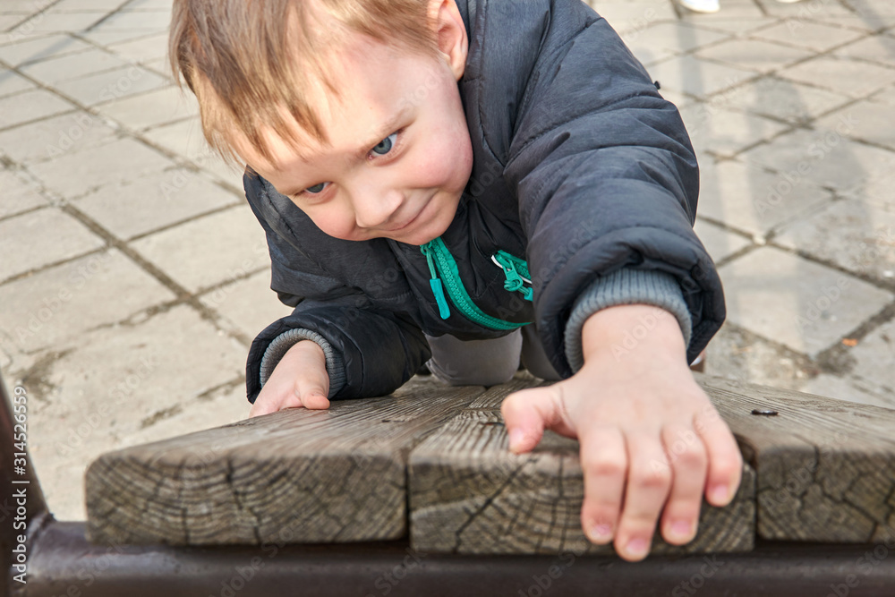 Naklejka premium little boy is climbing on a wooden board.