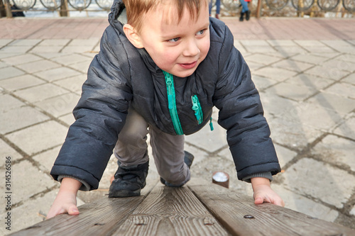 little boy is climbing on a wooden board.