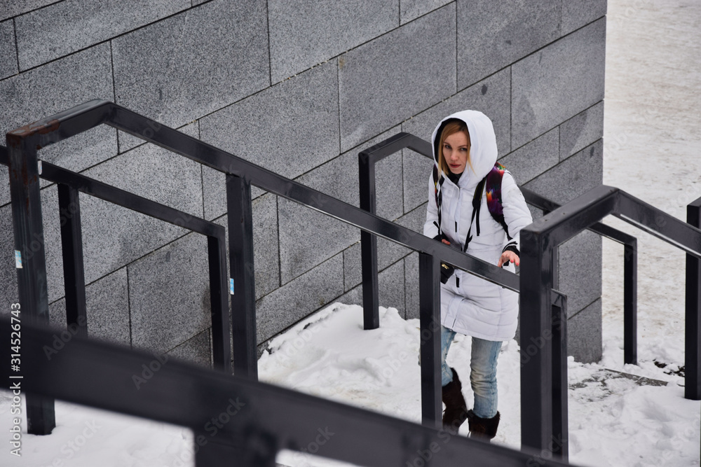 A woman with a camera in the winter climbs the stairs on the street. A woman with a camera in the winter climbs the stairs on the street.