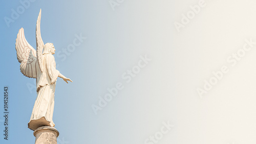 Statue of winged angel at Evangelical church Saint Nikolai at sunset and blue sky, Potsdam, Germany