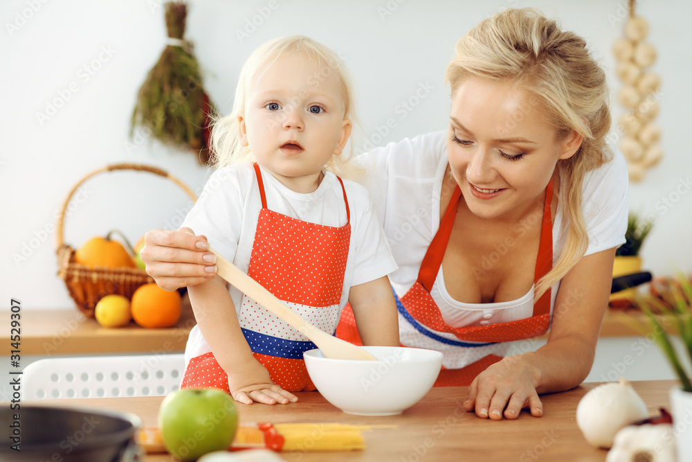 Happy mother and little daughter cooking in kitchen. Spending time all together, family fun concept Happy mother and little daughter cooking in kitchen. Spending time all together, family fun concept