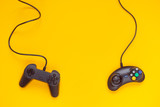 Two wired gamepads or video game controllers on yellow background. Top view, flat lay. Gaming, console industry