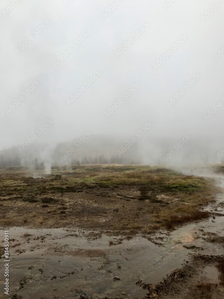 Nordic landscape in Haukadalur valley (Iceland) on a cold autumn / winter day in the geothermal area of The Great Geysir: mud roads, rocks & volcanic nature releasing hot water through geyser springs Nordic landscape in Haukadalur valley (Iceland) on a cold autumn / winter day in the geothermal area of The Great Geysir: mud roads, rocks & volcanic nature releasing hot water through geyser springs