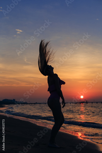 The girl in a pink swimsuit waves her hair on the beach. sea and