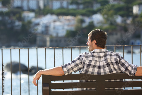 Relaxed man contemplating views sitting on a bench