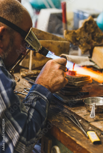 Jeweler at work with a propane burner in a jewelry workshop. Fire close up.