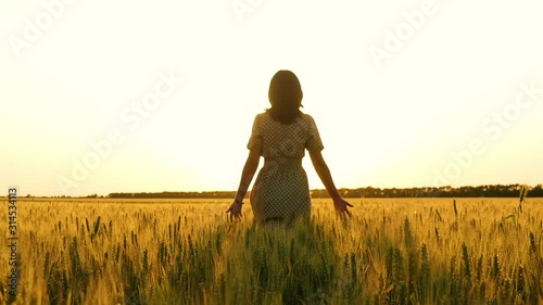 Wallpaper Mural Girl in a dress walking across the field towards the sunset, touching her ears of wheat. Torontodigital.ca