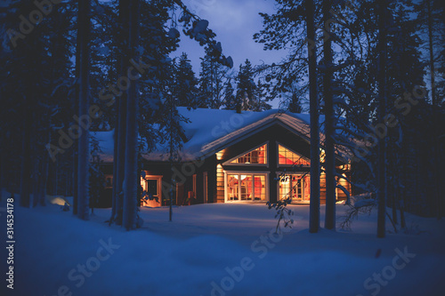 A cozy wooden cabin cottage chalet house covered in snow near ski resort in wint Fototapete