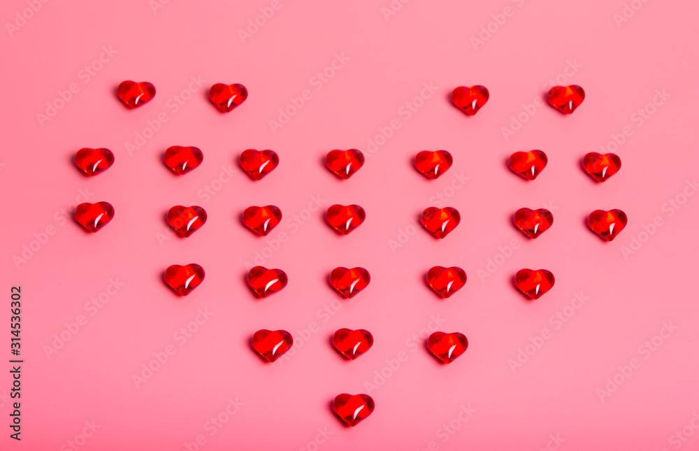 Heart made with red heart-shaped crystals on pink background. Valentine's Day.