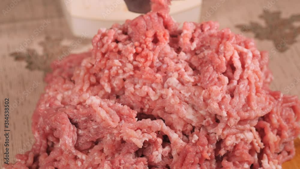 Filling comes out through a meat grinder sieve. Meat grinder close up. Pile of chopped meat. Mincer machine with fresh chopped meat. Process of meat grinding in the kitchen with mincing machine Filling comes out through a meat grinder sieve. Meat grinder close up. Pile of chopped meat. Mincer machine with fresh chopped meat. Process of meat grinding in the kitchen with mincing machine