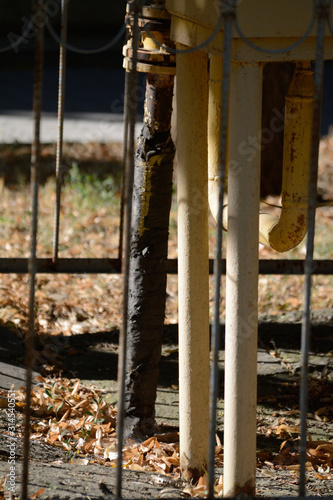 Old yellow metal pipes behind fence
