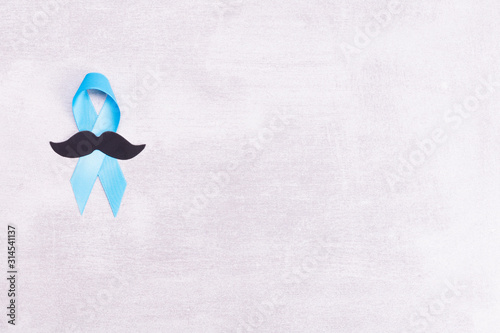 Healthcare and medicine concept - blue prostate cancer awareness ribbon and paper black mustache, achalasia and adrenocortical cancer, on gray background, flat lay, top view, place for text photo