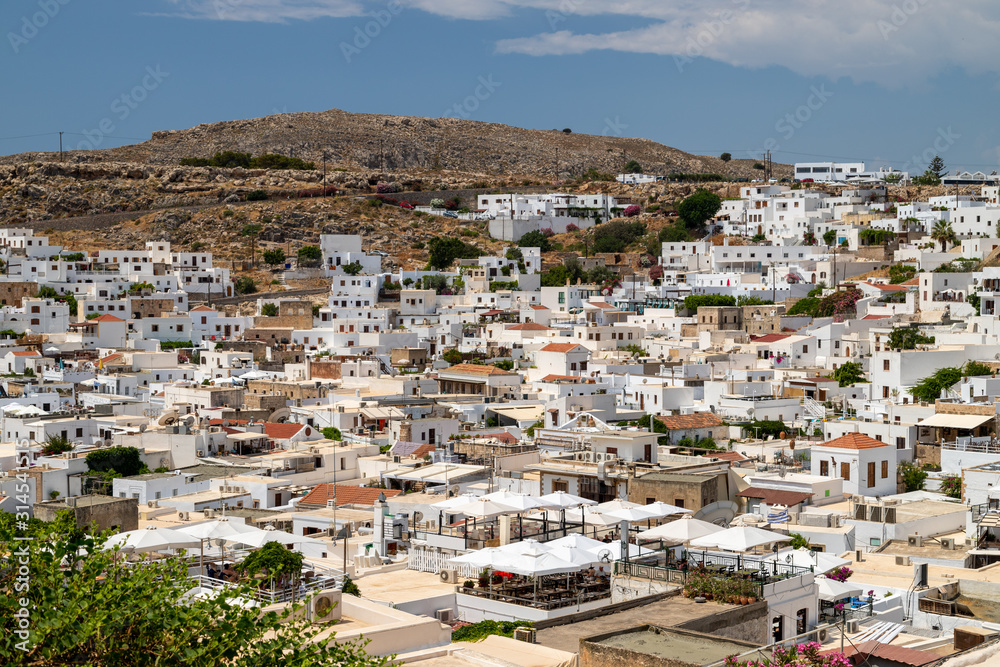 View at the city of Lindos on Greek island Rhodes with white houses and mountain in the background