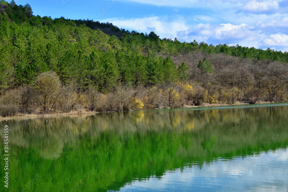 Beautiful lake, forest and mountains in early spring. Bashtanovka village, Crimea. A very beautiful spring landscape: forest, mountains, clouds. For cards, calendars, design.Spring forest