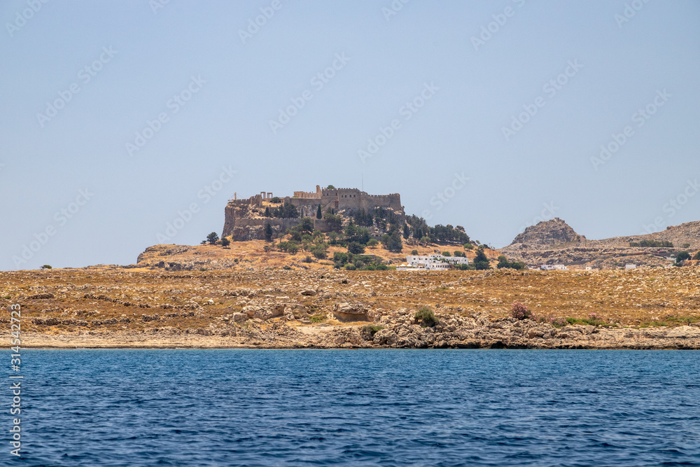 View from a motor boat on the mediterranean sea at the rocky coastline near Lindos on the eastside of Greek island Rhodes View from a motor boat on the mediterranean sea at the rocky coastline near Lindos on the eastside of Greek island Rhodes