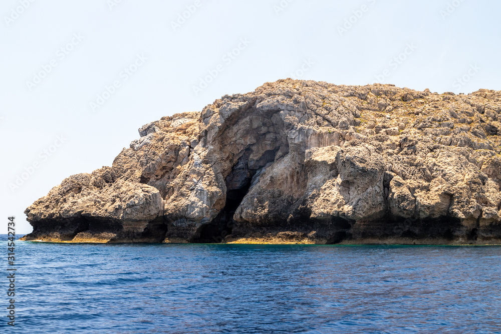 View from a motor boat on the mediterranean sea at the rocky coastline near Lindos on the eastside of Greek island Rhodes