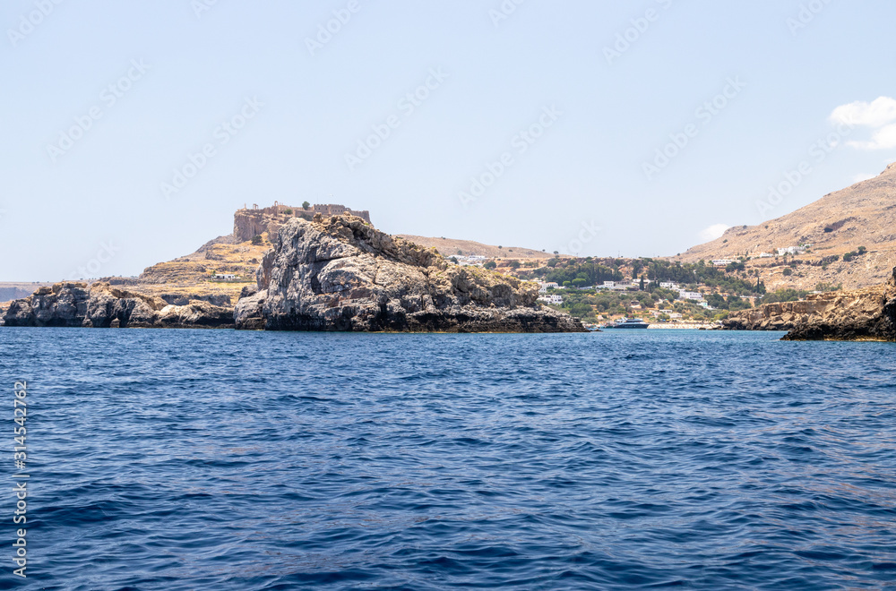 View from a motor boat on the mediterranean sea at the rocky coastline near Lindos on the eastside of Greek island Rhodes