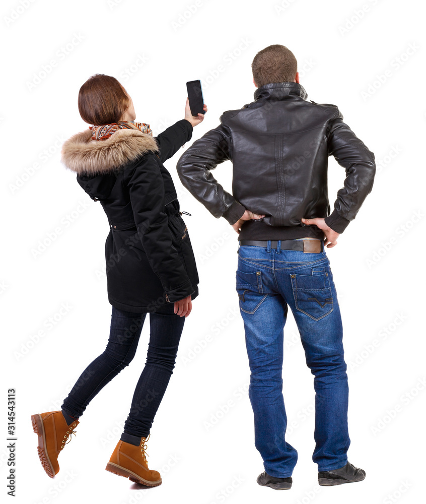 Back view of couple in winter jacket photographed on a mobile phone in winter jacket. Back view of couple in winter jacket photographed on a mobile phone in winter jacket.