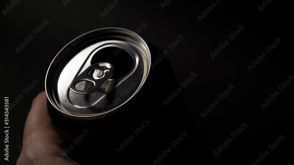 Aluminum can in a hand on a black background. Fresh drink. Interior poster. Aluminum can in a hand on a black background. Fresh drink. Interior poster.