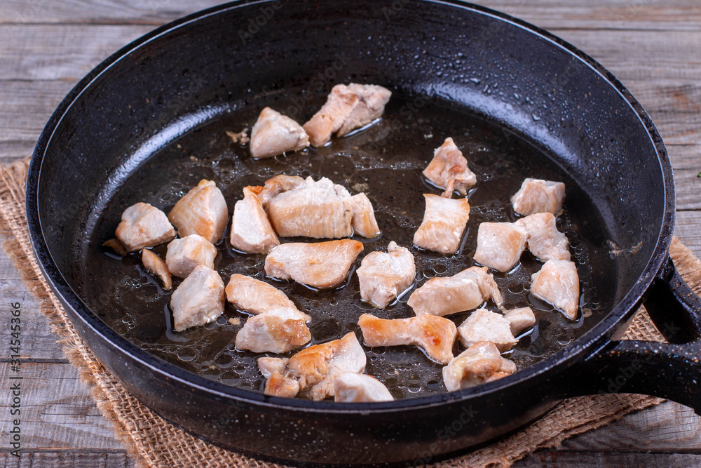 Chopped chicken fillet fried on frying pan with raw meat Chopped chicken fillet fried on frying pan with raw meat