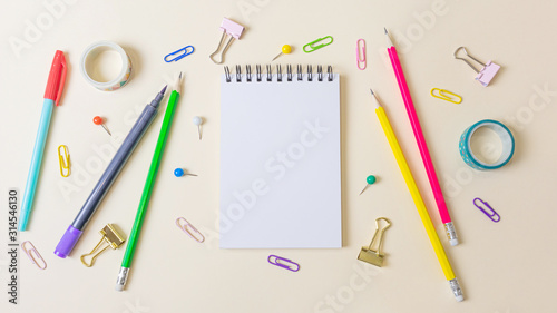 Pens, paper clips, notebook and other stationery on a light pastel background. Banner. Place for text, minimalism. School, office, education concept.