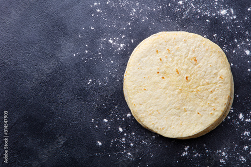 Tortillas, flat breads on dark grey background. Copy space. Top view.