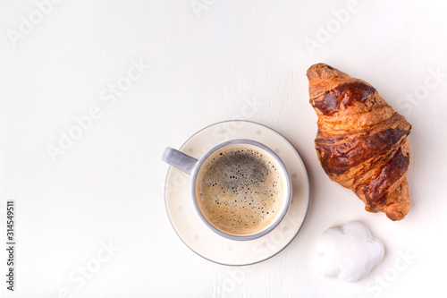 Fototapeta Naklejka Na Ścianę i Meble -  Croissant, glazed cookies and a cup of coffee on a white wooden table. Morning still life. Top view with space for text. Flat lay composition. Background for restaurant, bakery, cafe.