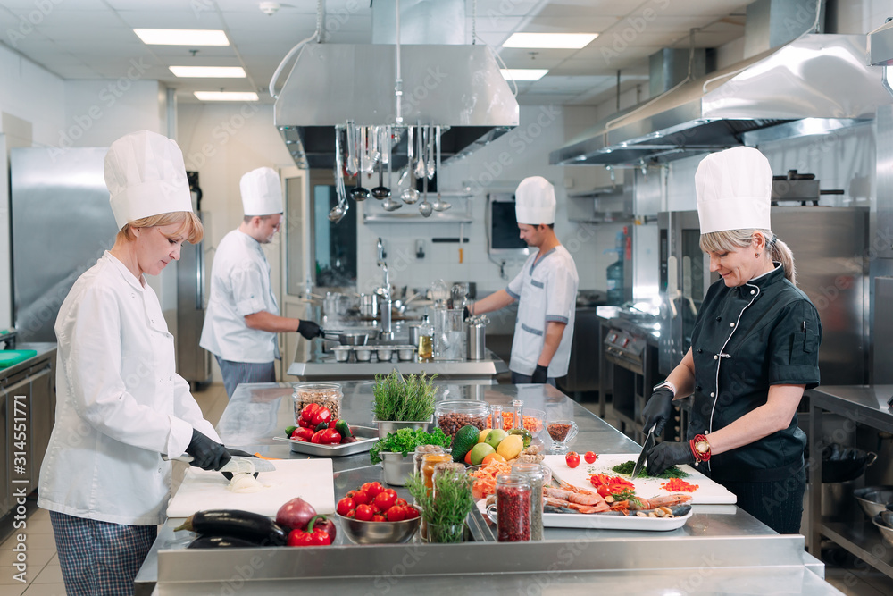cooks cut vegetables in the restaurant kitchen. cooks cut vegetables in the restaurant kitchen.