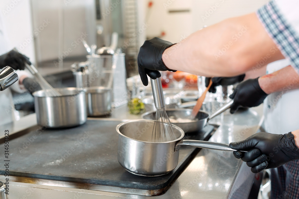 Cooks prepare meals on an electric stove in a professional kitchen in a restaurant or hotel. Cooks prepare meals on an electric stove in a professional kitchen in a restaurant or hotel.