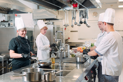 Cooks prepare meals on an electric stove in a professional kitchen in a restaurant or hotel.