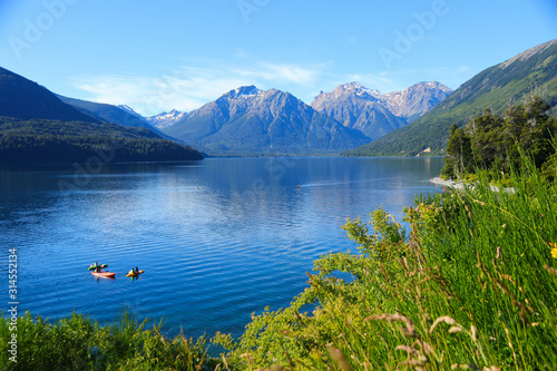 Tourists enjoying the blue waters of Mascardi lake in a canoe, south of San Carlos de Bariloche in Patagonia, Argentina, under a snow-covered mountain of the Andes