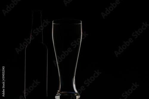 Empty dark bottle and glass on a dark background