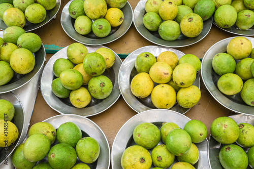 Heap of fresh raw green and ripe guavas on aluminium trays at Singapore local market