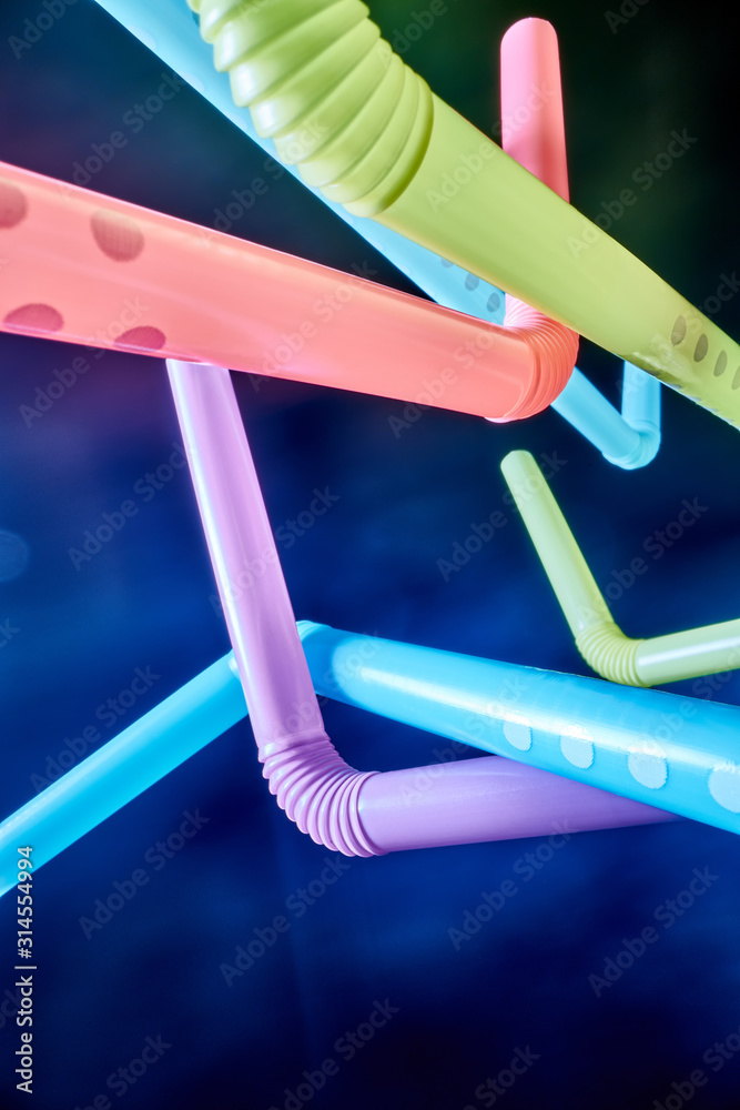 Background from multi-colored plastic cocktail tubes on a dark background Background from multi-colored plastic cocktail tubes on a dark background