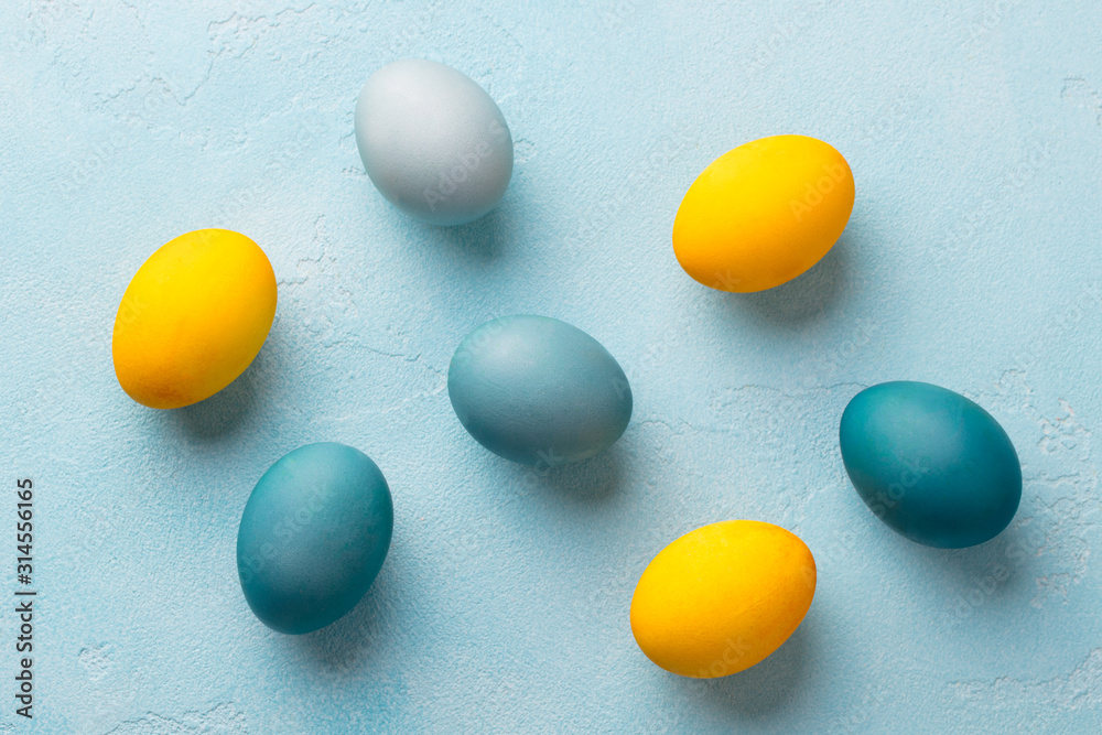Colorful Easter eggs on blue background. Flat lay composition. Top view. Copy space.