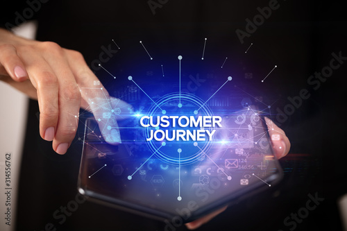 Businessman holding a foldable smartphone with CUSTOMER JOURNEY inscription, new business concept