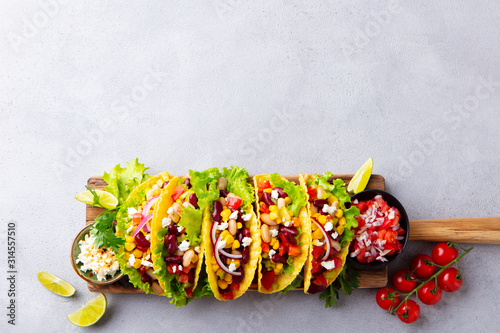 Taco with mixed vegetables, beans on cutting board. Grey background. Copy space. Top view.
