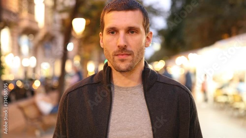 Front view portrait of a serious sad man walking alone in the night in the street