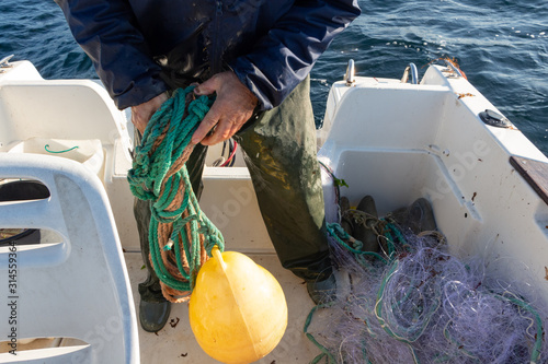 Fisherman winding a rope on the deck of his boat after fishing
