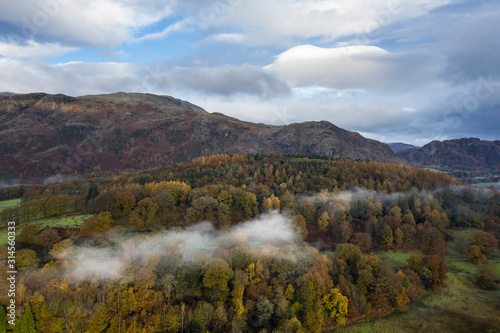 Stunning aerial drone landscape image from in the clouds looking down on hills and valleys on a vibrant Autumn Fall morning