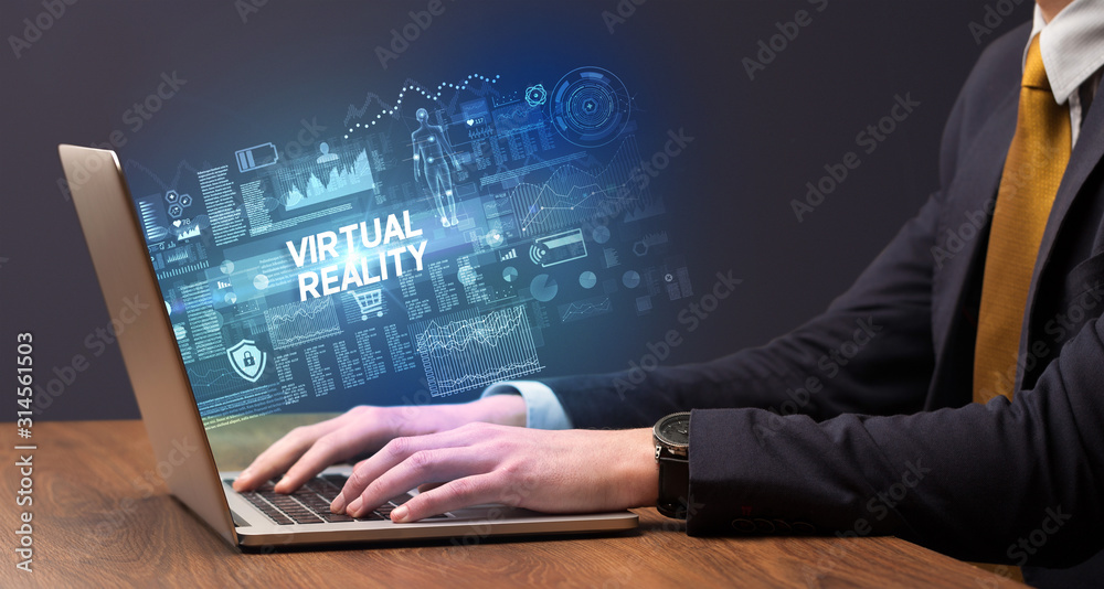 Businessman working on laptop with VIRTUAL REALITY inscription, cyber technology concept Businessman working on laptop with VIRTUAL REALITY inscription, cyber technology concept