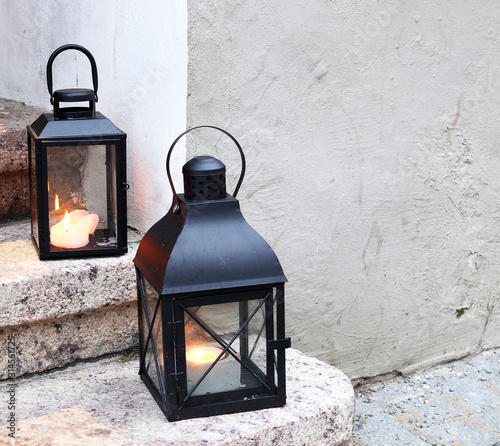 Christmas lantern with a candle on the steps of the house