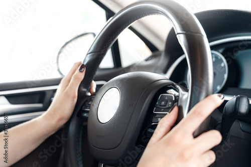 Mode of Transport. Electric car interior close-up woman holding steering wheel driving
