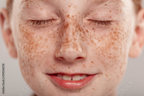 Inclusive Beauty. Girl with freckles standing isolated on grey clsoed eyes dreaming happy close-up
