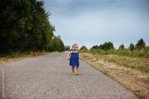 Fototapeta Naklejka Na Ścianę i Meble -   one-year-old girl barefoot on   country road.