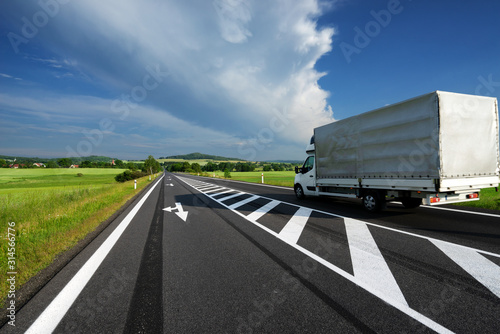 Delivery van transporting goods on asphalt road in a rural landscape