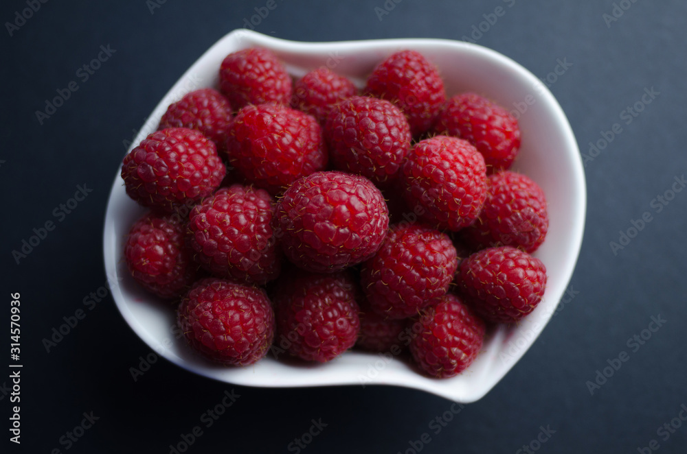 Fresh raspberries in a white pot. Flat view of red berries in a nice small white pot Fresh raspberries in a white pot. Flat view of red berries in a nice small white pot
